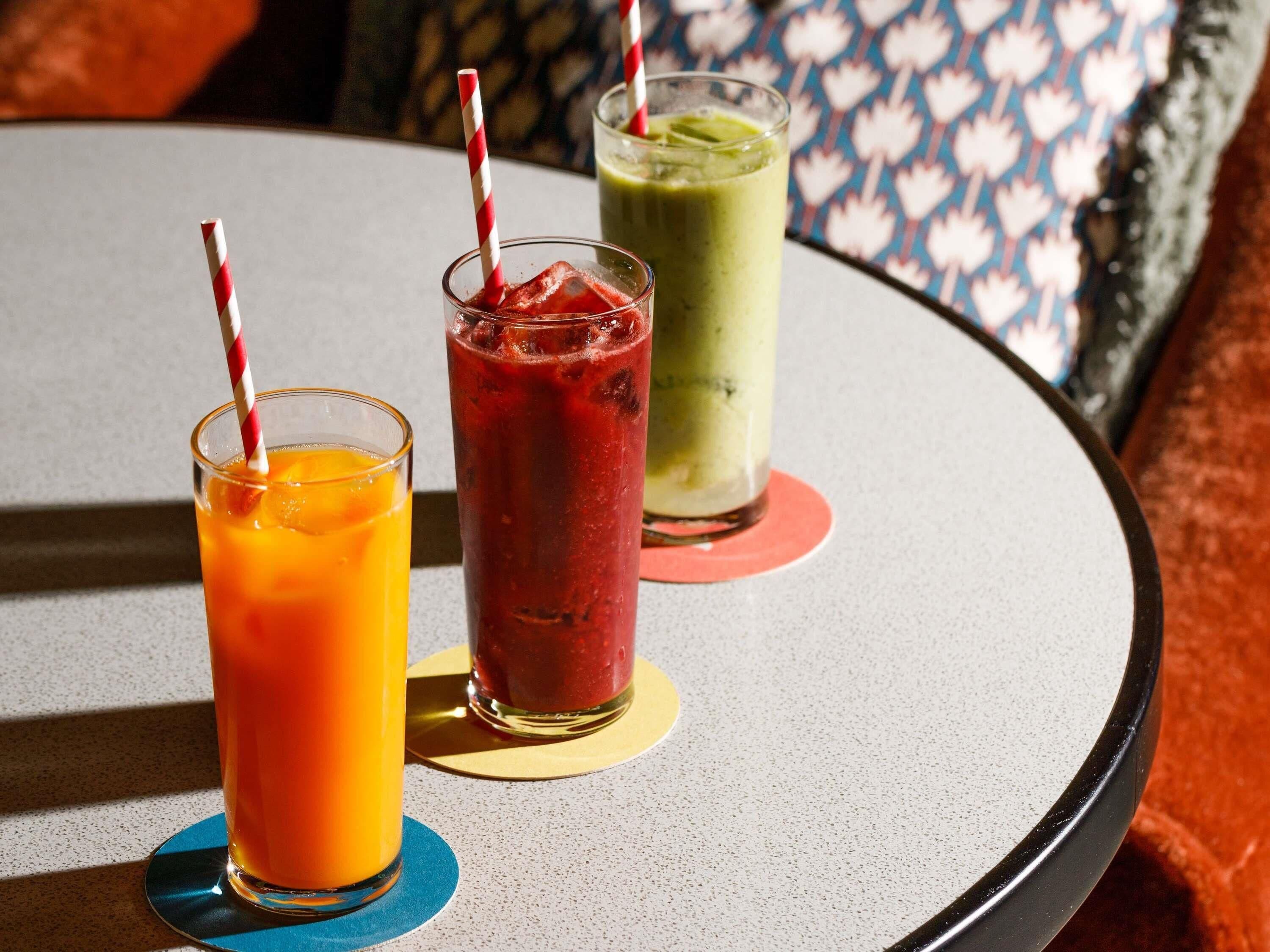 Tres bebidas sobre una mesa con posavasos.