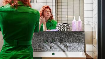 Ein Badezimmer mit Spiegel, Waschbecken und Toilettenartikeln.