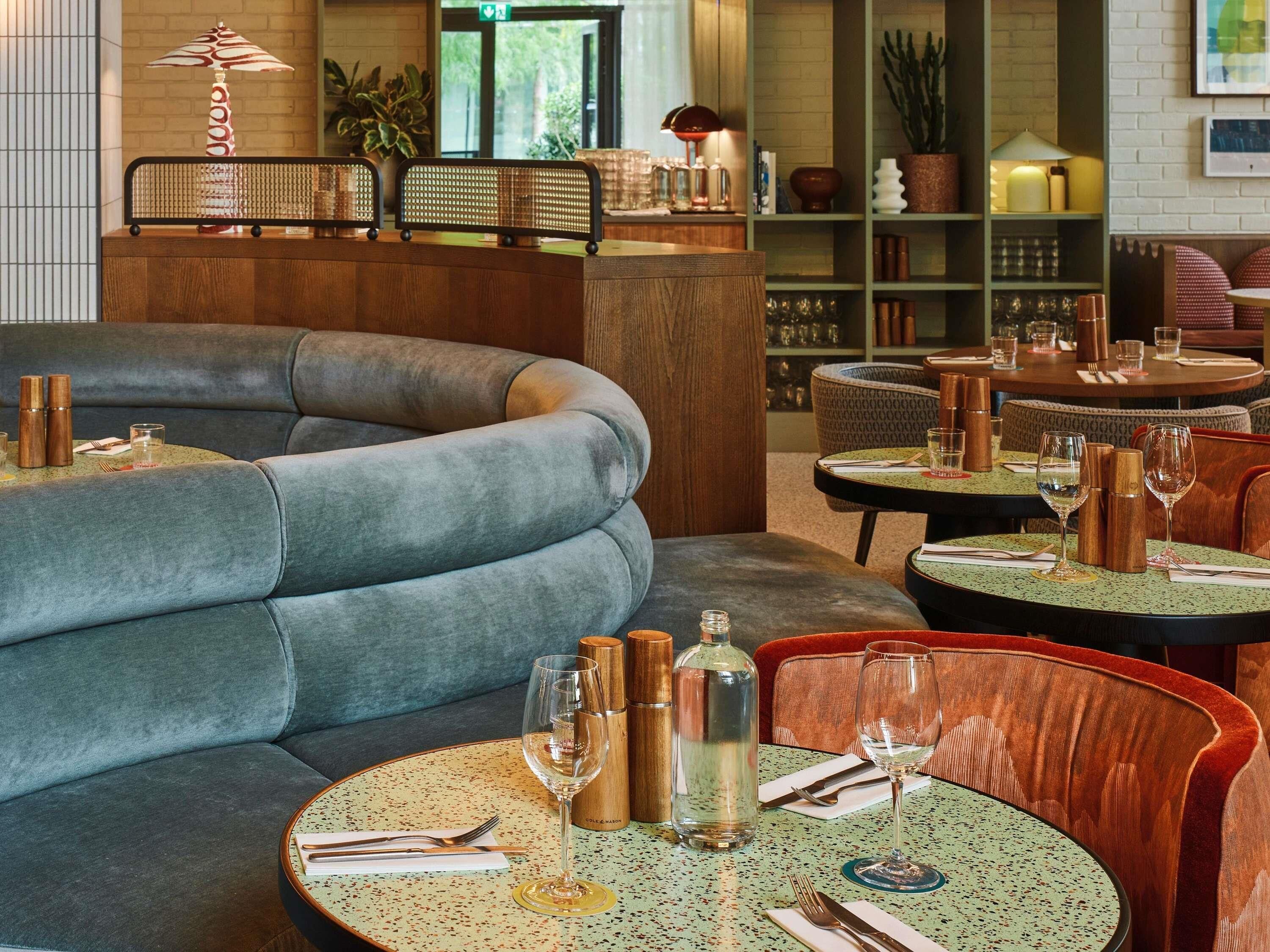 Een restaurant interieur met ronde tafels, stoelen en een bank.