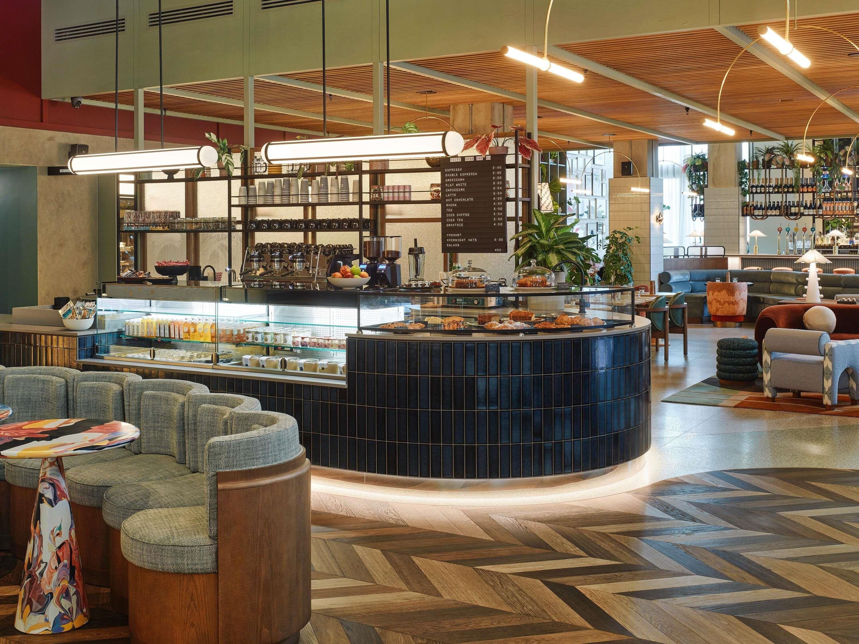 Een modern café met een centrale toonbank, een zithoek en een menubord.