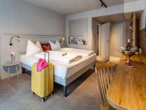 A hotel room with a bed, a wooden dining table, a suitcase, and a mirror. - Ibis Styles Graz Messe (Graz)