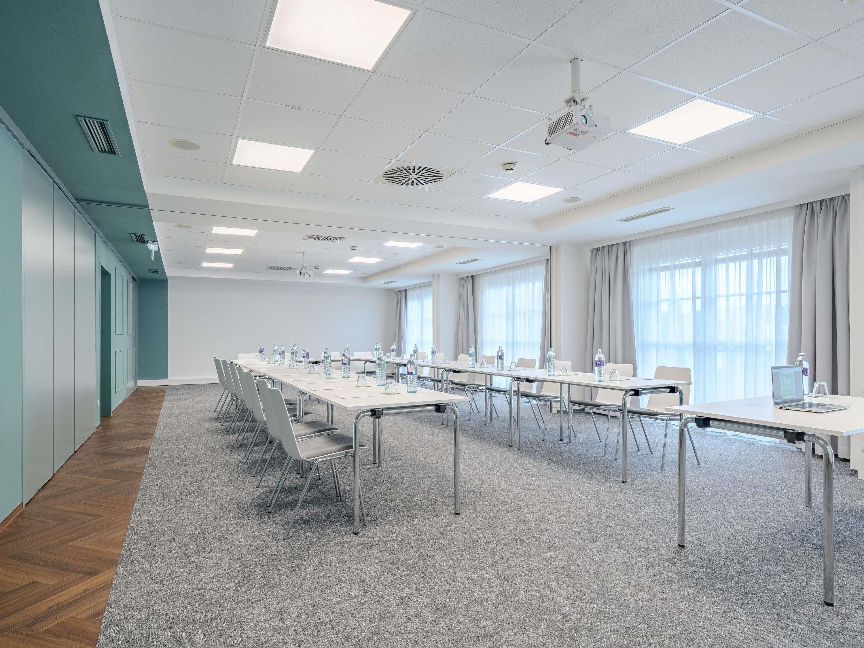 Ein Konferenzraum mit einem langen Tisch, Stühlen und einem Projektor.
