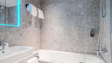 Ein modernes Badezimmer mit einer Duschkabine, einer weißen Badewanne, einem Waschbecken inklusive Spiegel und einem Handtuchhalter.