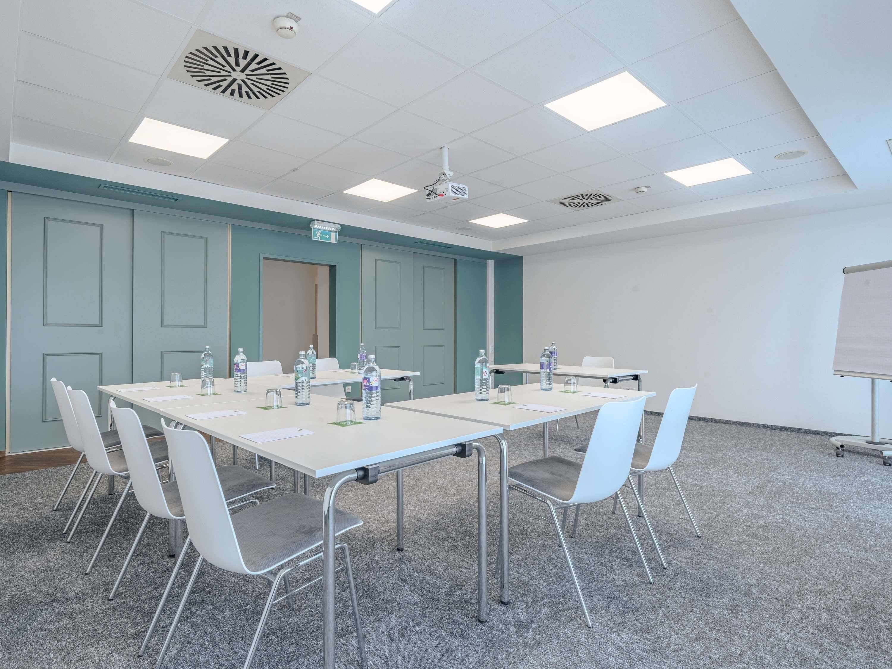 A conference room with a long table, chairs, water bottles, a projector, and a whiteboard.