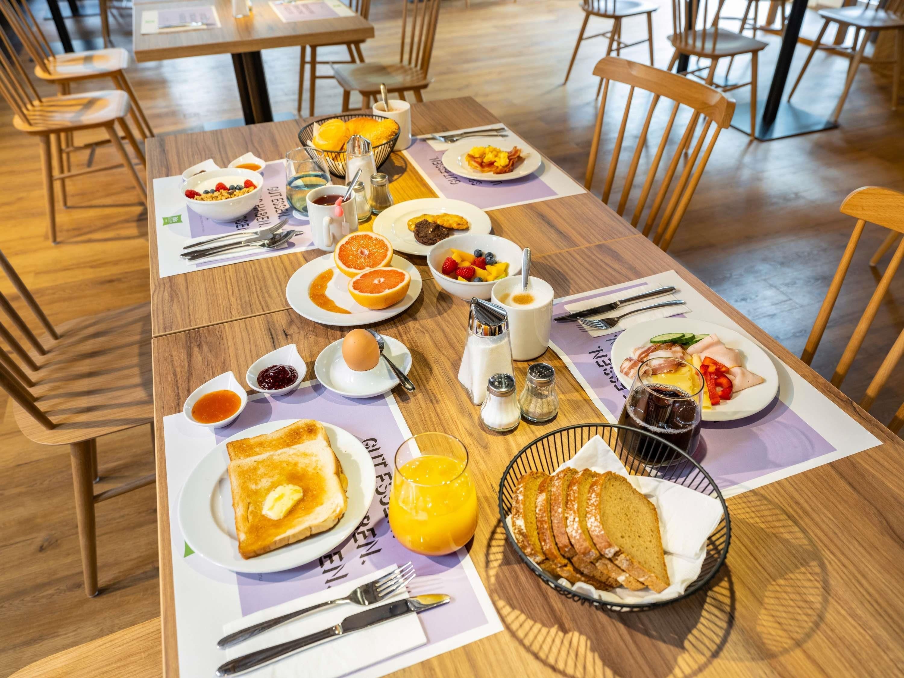 A breakfast setting with a variety of food items, including toast, fruit, eggs, and beverages.