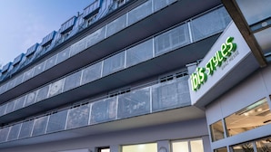 Un bâtiment moderne avec une enseigne indiquant « ibis styles » et des balcons dotés de garde-corps en métal.