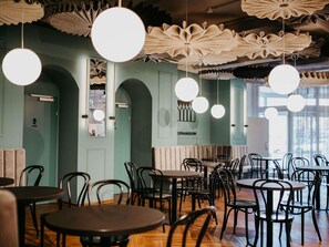 A restaurant interior with round tables, black chairs, and hanging paper lanterns. - Ibis Styles Graz Messe (Graz)
