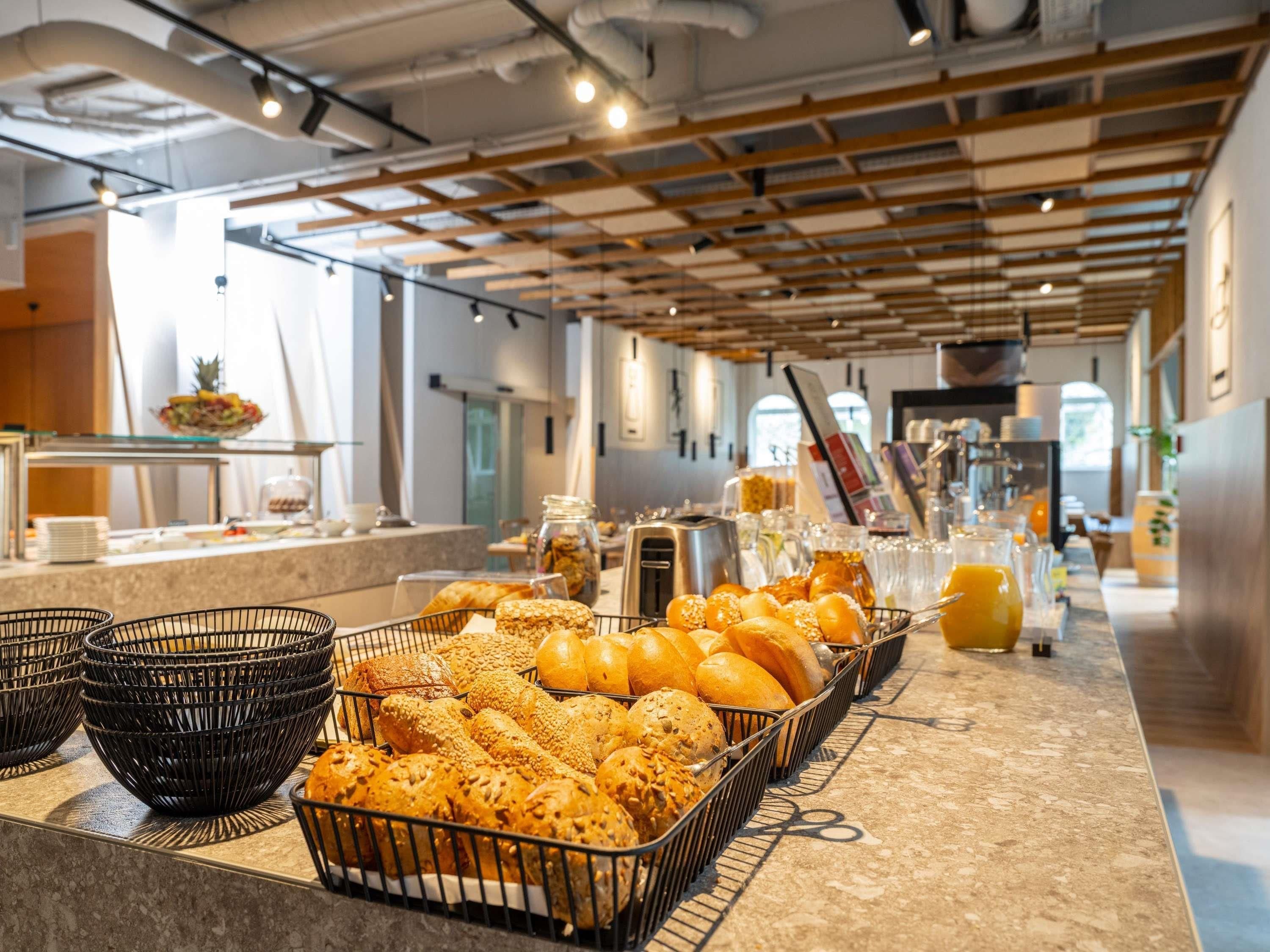 A breakfast buffet with various breads and pastries, a coffee station, and a juice bar.