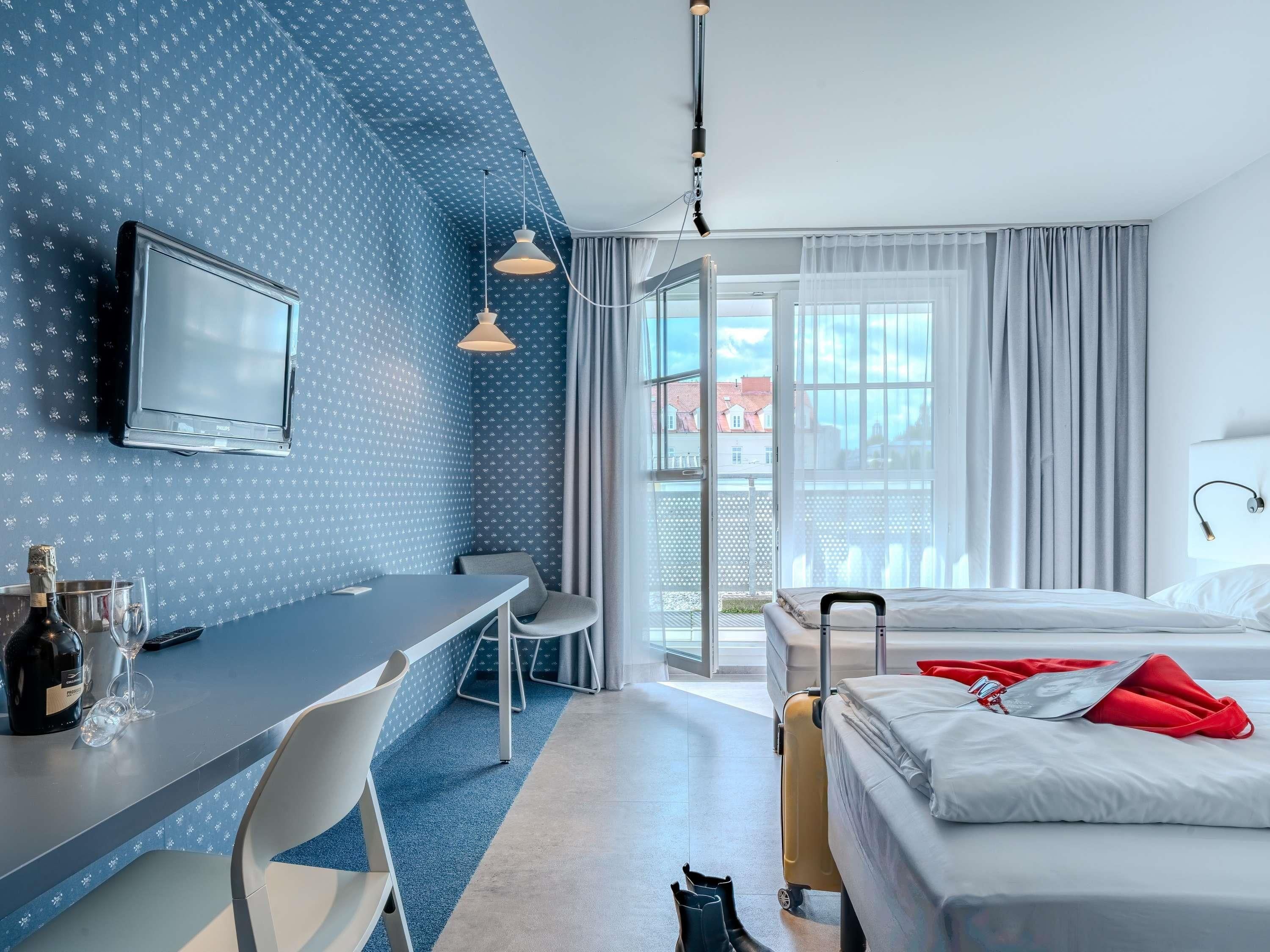 Camera d'albergo con un letto, una scrivania con una sedia, un televisore e una valigia.