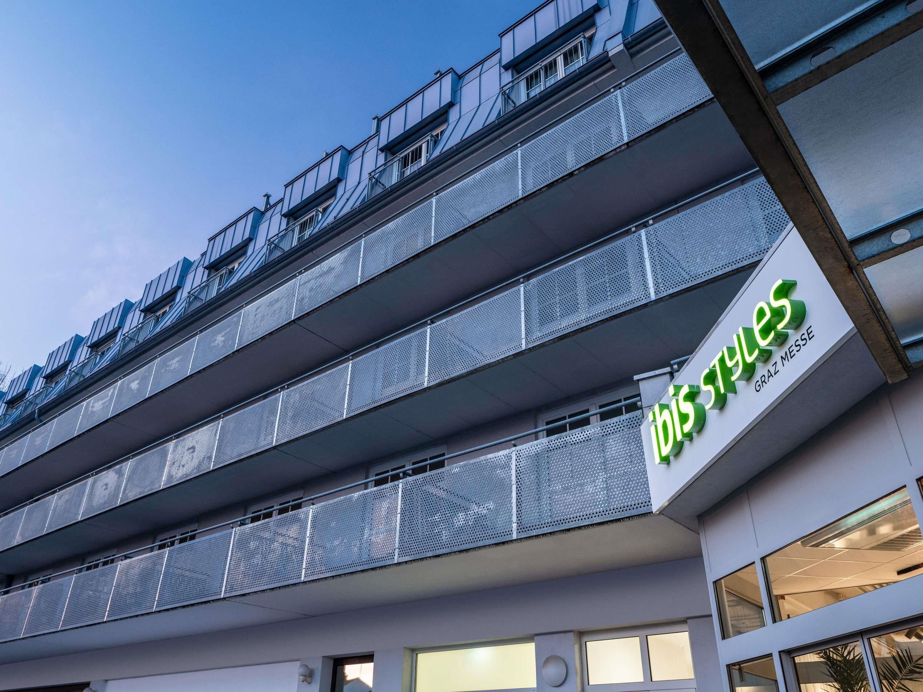 A modern building with a sign reading 'ibis styles' and balconies with metal railings.