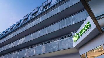 A modern building with a sign reading 'ibis styles' and balconies with metal railings.