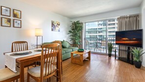 Relax in this stylish living room with a dining table for two, a sofa, and a flat-screen TV.