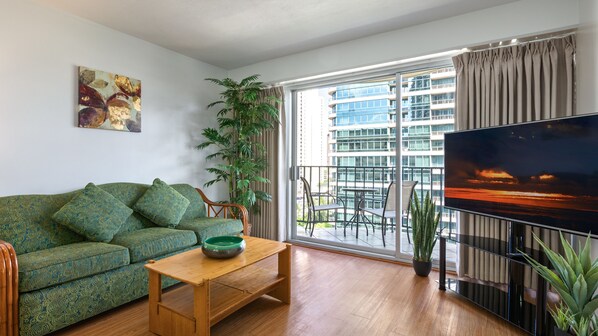 Relax in this stylish living room with a sofa, coffee table, and large flat-screen TV. Enjoy the view from the sliding glass door leading to the outdoor balcony.