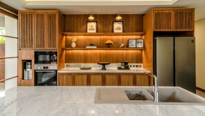 Eine moderne Küche mit Holzschränken, einem Edelstahlkühlschrank und einer Marmorarbeitsplatte.