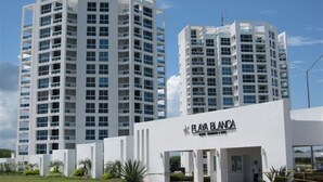 A modern hotel with multiple high-rise buildings, featuring balconies and a prominent 'Playa Blanca' sign.