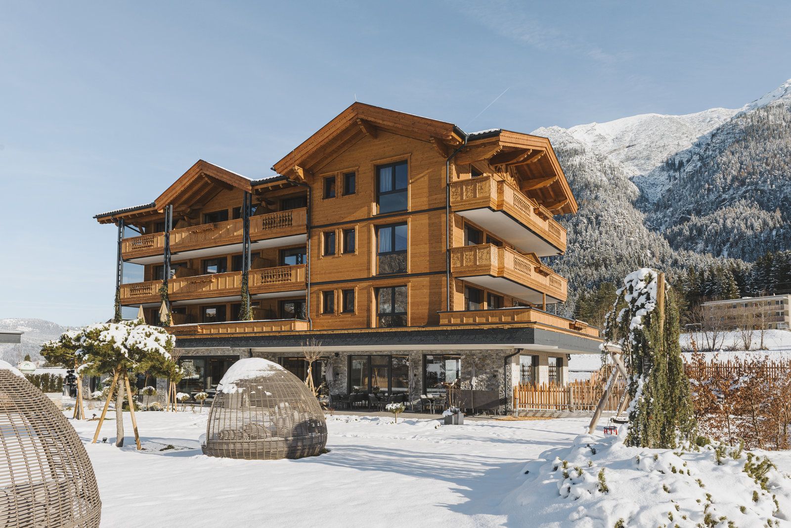 Un edificio de madera de varios pisos con balcones, rodeado de montañas nevadas.
