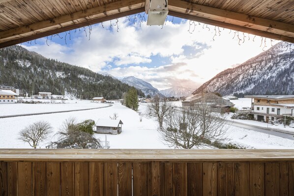 Enjoy breathtaking views of snow-covered mountains and buildings from this balcony.