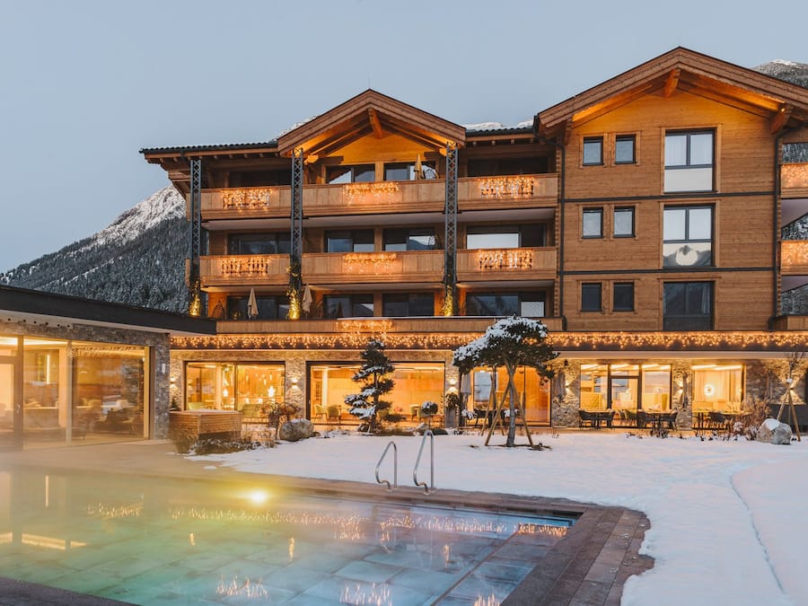 A multi-story hotel with a pool area, surrounded by snow-covered mountains.
