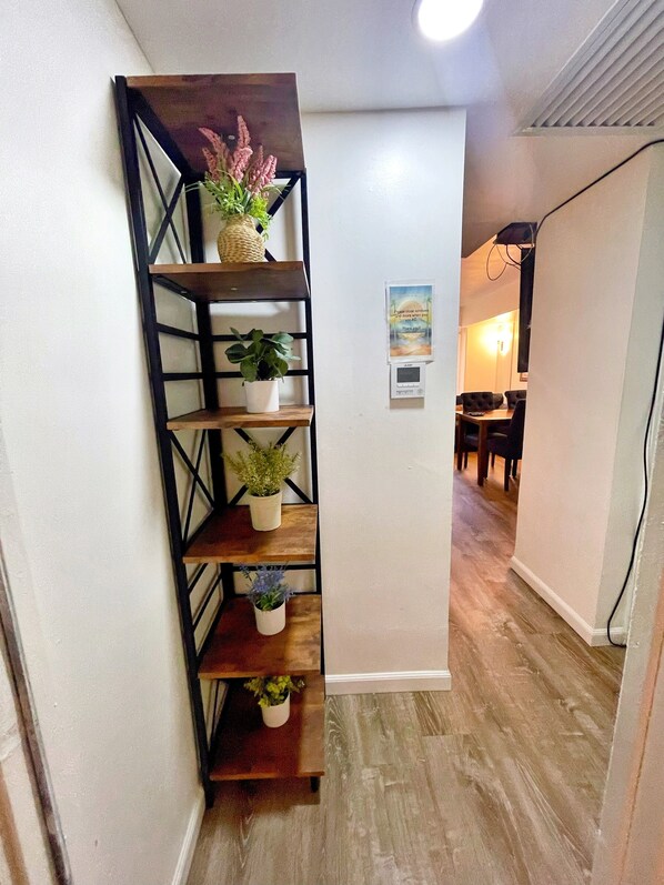 Una escalera con estructura metálica negra y peldaños de madera, que conduce a una habitación con suelo de madera y una puerta.