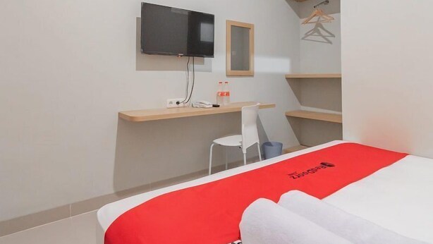 A hotel room with a bed, a desk, a chair, a TV, and a wardrobe. - Sans Stay Karapitan Street (Bandung)