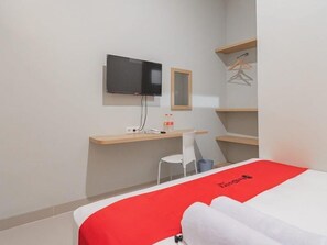 Habitació d'hotel amb llit, escriptori, cadira, televisió i armari.