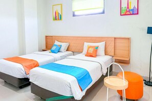 A hotel room with two beds, a small table, and a chair. - Sans Stay Karapitan Street (Bandung)