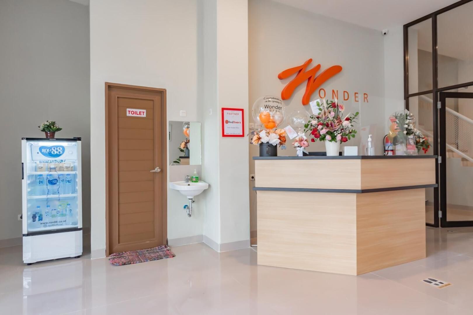 A reception area with a wooden counter, a sink, a toilet, and a vending machine.