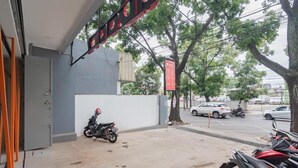 A motorcycle parked outside a building with a signboard above. - Sans Stay Karapitan Street (Bandung)