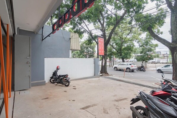 A motorcycle parked outside a building with a signboard above. - Sans Stay Karapitan Street (Bandung)