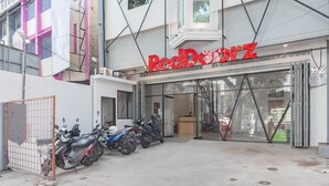 A RedDoorz store with a glass entrance and several parked scooters outside. - Sans Stay Karapitan Street (Bandung)