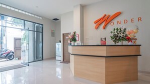 A reception desk with a wooden finish and a sign that reads "WONDER". - Sans Stay Karapitan Street (Bandung)