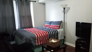 A bedroom with a bed, a TV, a lamp, and a small table. - Luxury Cherry Blossom Suite 15 min from Downtown (Washington)