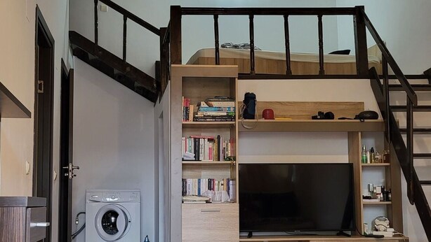A room with a bunk bed, a washing machine, a TV, and a bookshelf. - Cute Compact One BHK Apartment Near Center ! 10 mins walk (Cluj-Napoca)
