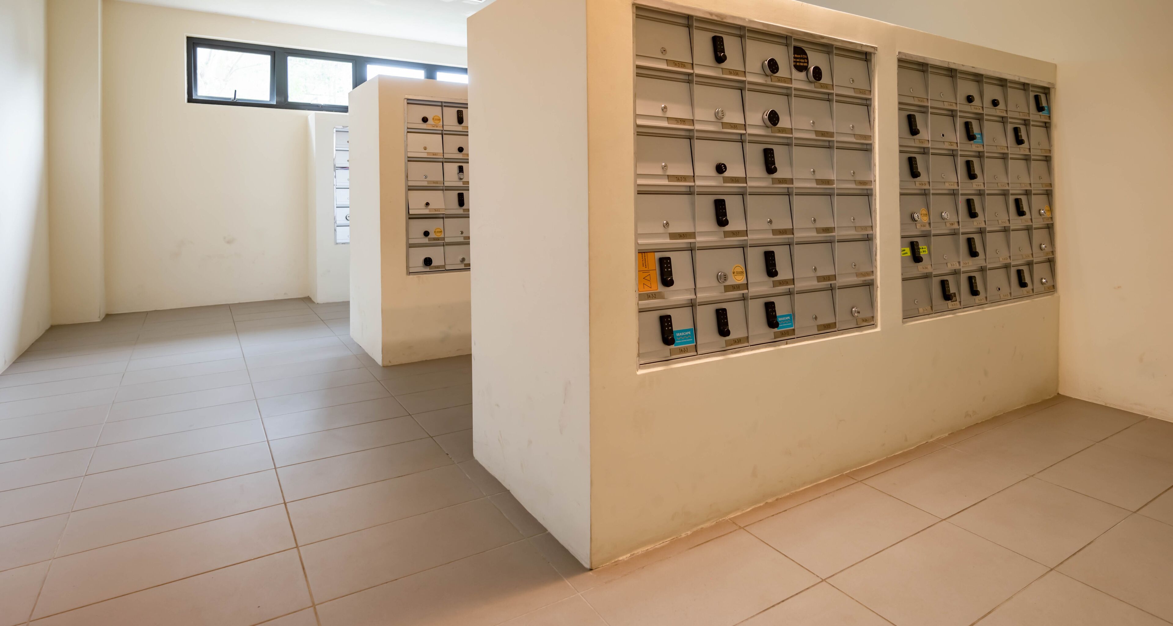 A room with a tiled floor and a wall with multiple storage units containing various items.