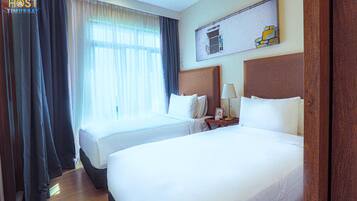 A hotel room with two beds, a nightstand with a lamp, and a painting on the wall.