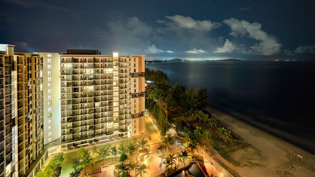 A high-rise hotel with multiple balconies overlooking a beach and a calm sea. - Timurbay beachfront by Perfect Host (Kuantan)