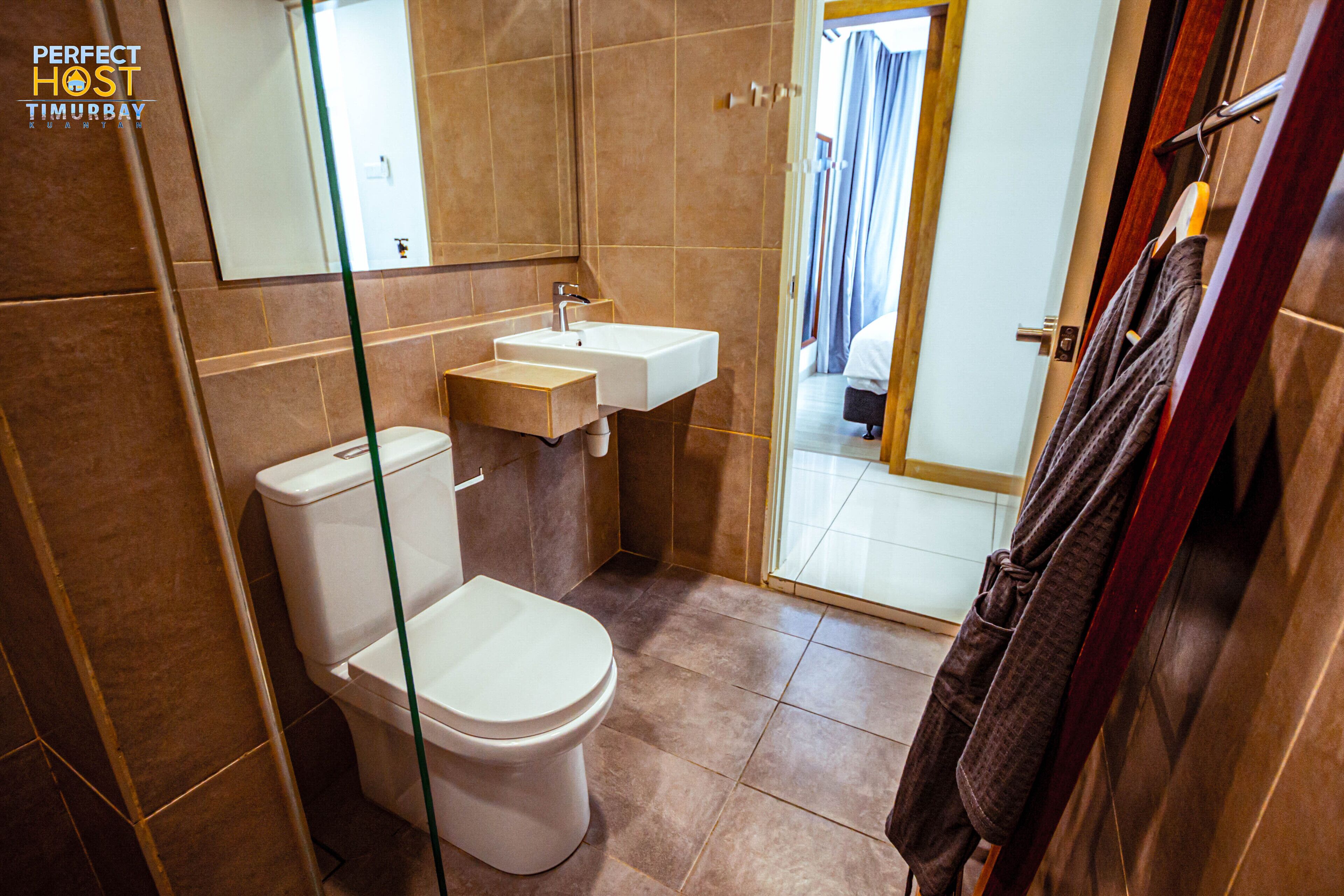 A bathroom with a toilet, sink, and mirror. There is a towel rack with a towel hanging on it.