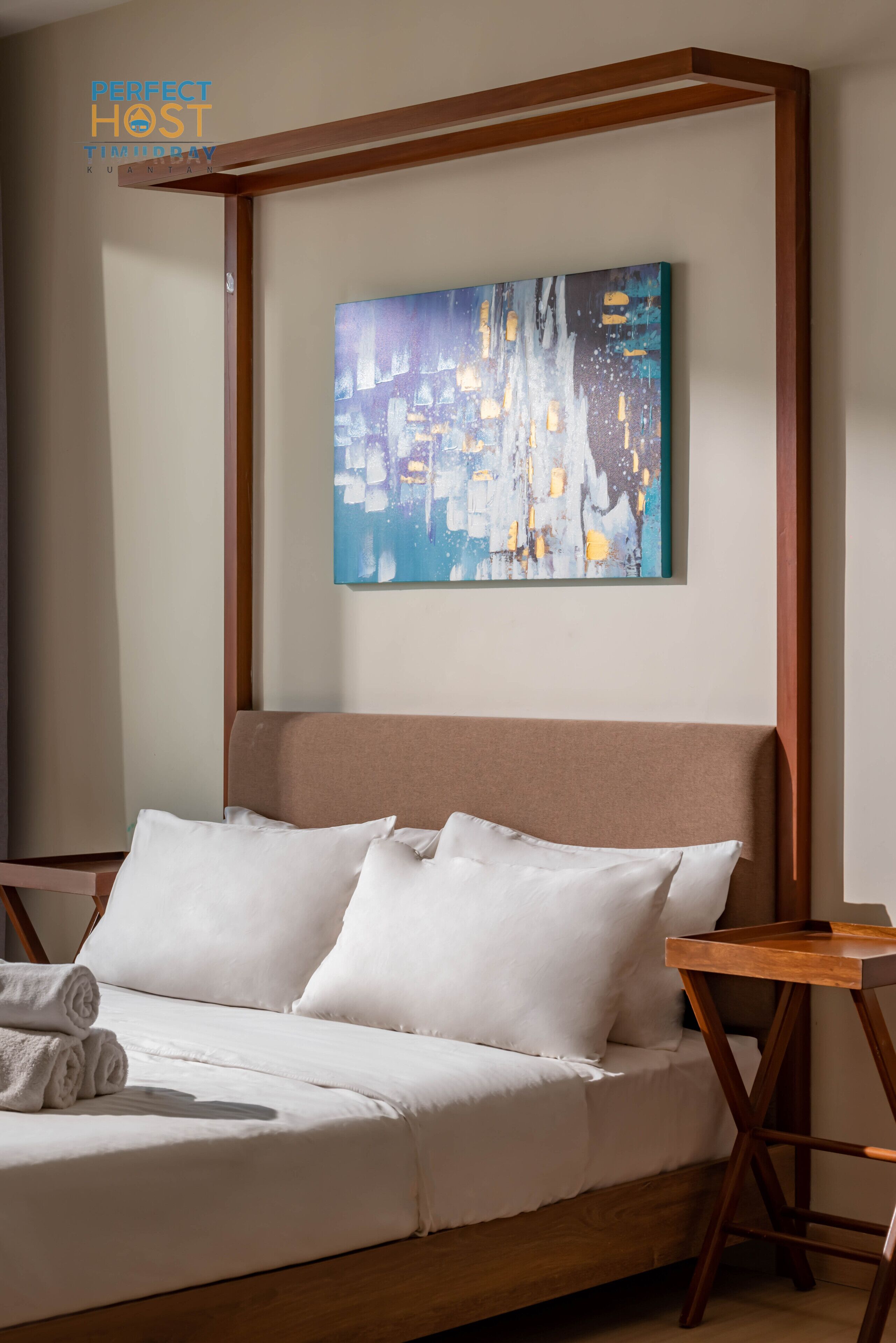 A neatly made bed with white linens and pillows, a wooden headboard, and a wooden nightstand with a lamp.