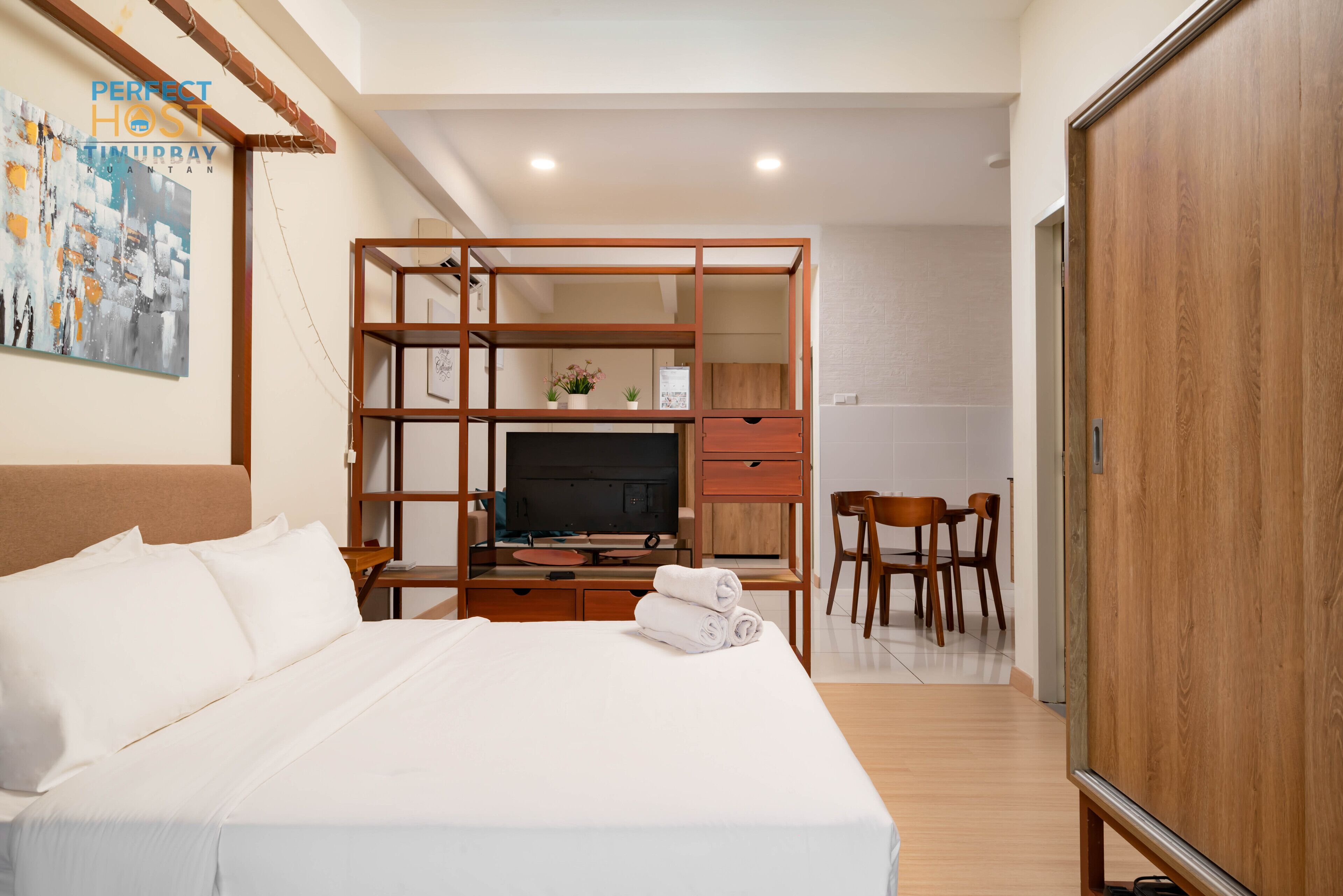 A hotel room with a large bed, a TV, a desk, and a wardrobe.