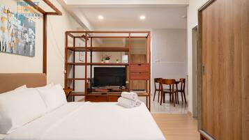 A hotel room with a large bed, a TV, a desk, and a wardrobe.