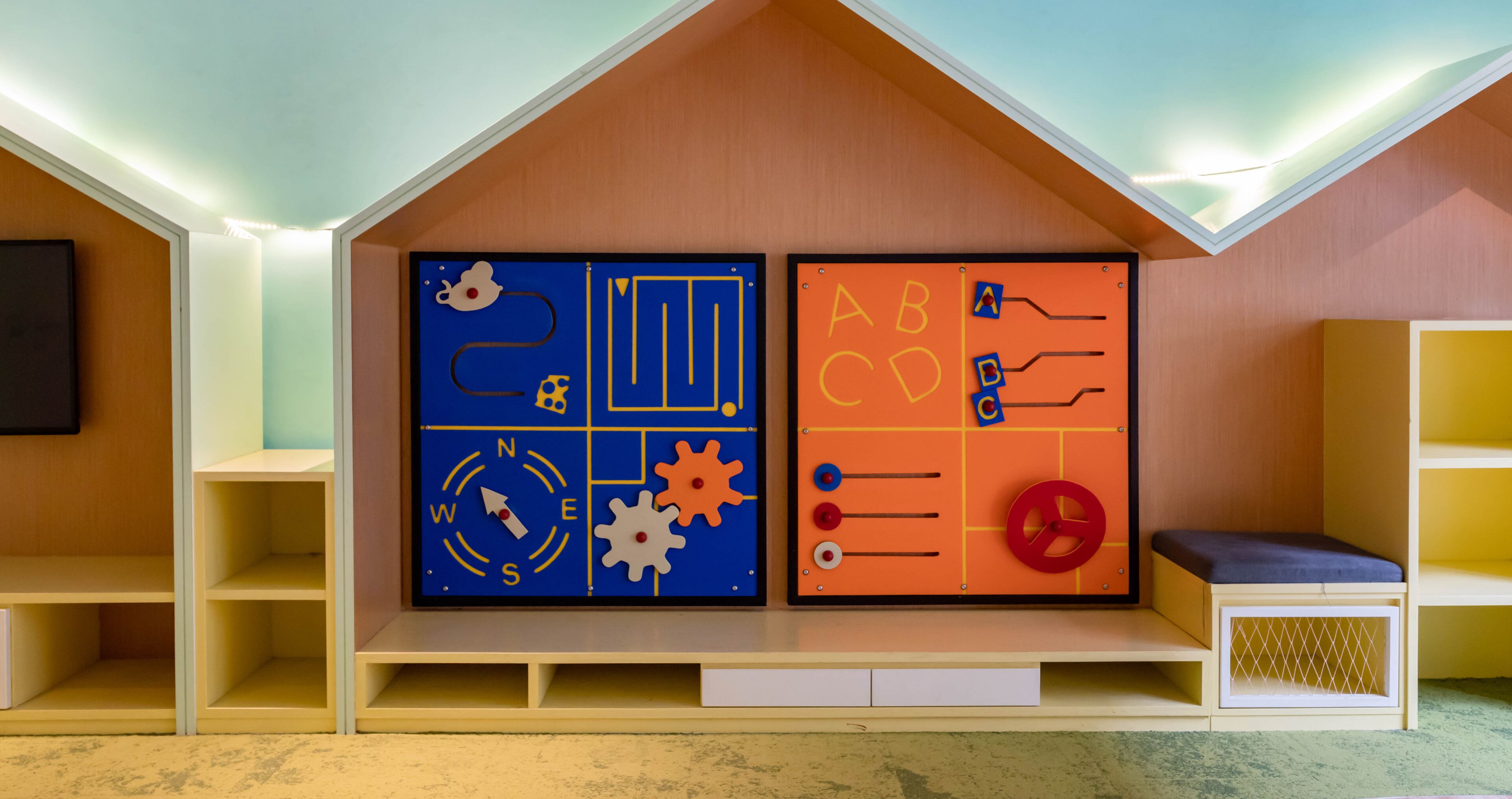 A children's play area with educational wall decorations, including a compass and alphabet learning tools.