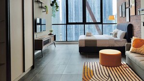 A modern bedroom with a large bed, a desk, and a view of a cityscape through floor-to-ceiling windows. - Scarletz Suites KLCC by Mykey (Kuala Lumpur)