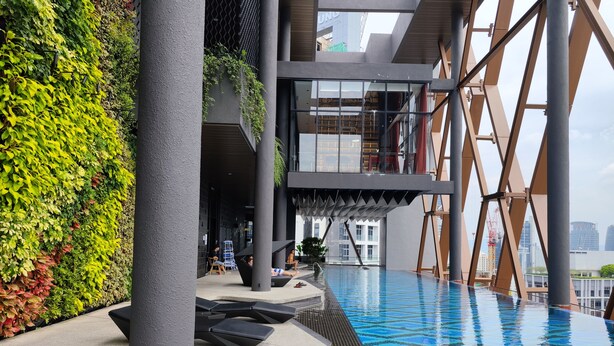 A modern outdoor pool area with a glass-enclosed upper level and a green wall with plants. - Scarletz Suites KLCC by Mykey (Kuala Lumpur)