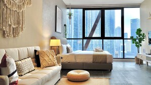 A modern bedroom with a large window, a ceiling fan, and a city view. - Scarletz Suites KLCC by Mykey (Kuala Lumpur)