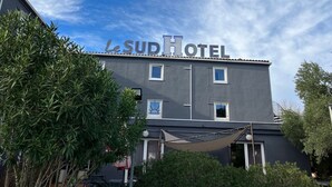 A hotel named "Le Sud Hotel" with a modern facade, multiple windows, and a covered outdoor seating area. - Le Sud Hotel (Mauguio)