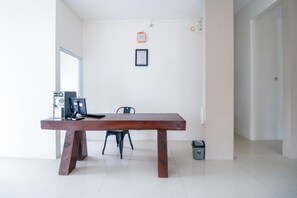 A modern office space with a wooden table, a chair, a computer, and a trash bin. - Urbanview Hotel AVA Banjarmasin (Banjarmasin)