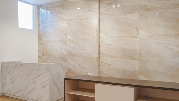 A modern room with a marble wall, a wooden floor, and a built-in desk with shelves. - Reddoorz Near Istana Plaza 3 (Bandung)