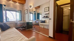 A modern hotel room with a large bed, a desk, and a seating area. - Appartamento Lamberti (Florence)