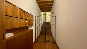 A narrow hallway with wooden lockers on the left and a metal gate leading to a staircase. - Appartamento Lamberti (Florence)