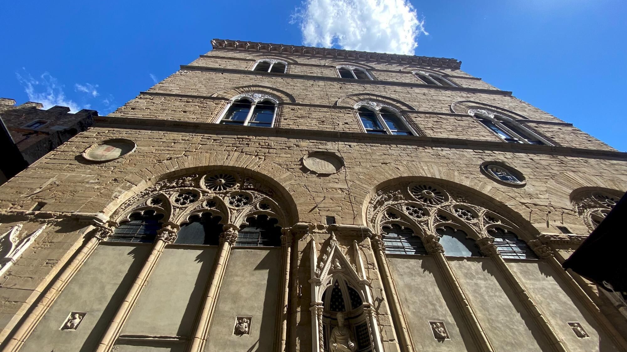 Ein historisches Gebäude im gotischen Stil, mit spitzbogigen Arkaden und aufwendigen Steinmetzarbeiten.